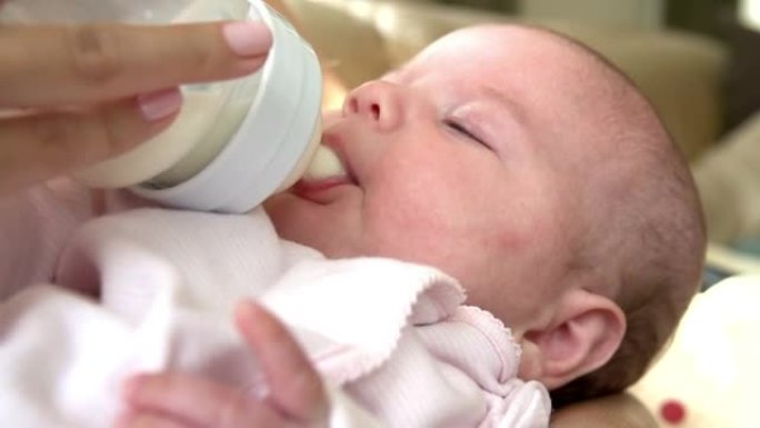 婴儿在托儿所从奶瓶中喂牛奶的特写