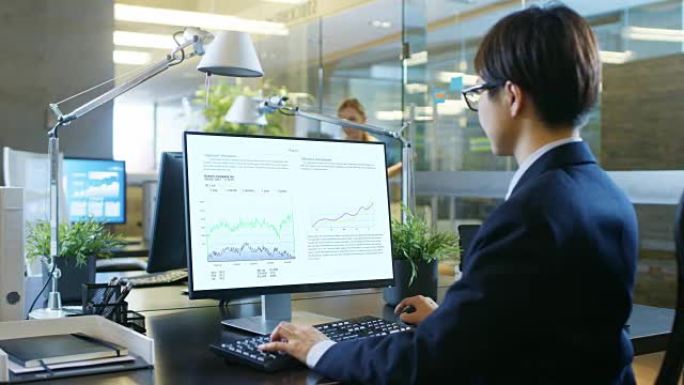 在办公室里，商人用电子表格、图表和统计数据在个人电脑上工作。他的同事坐在她对面。房间是由混凝土和玻璃