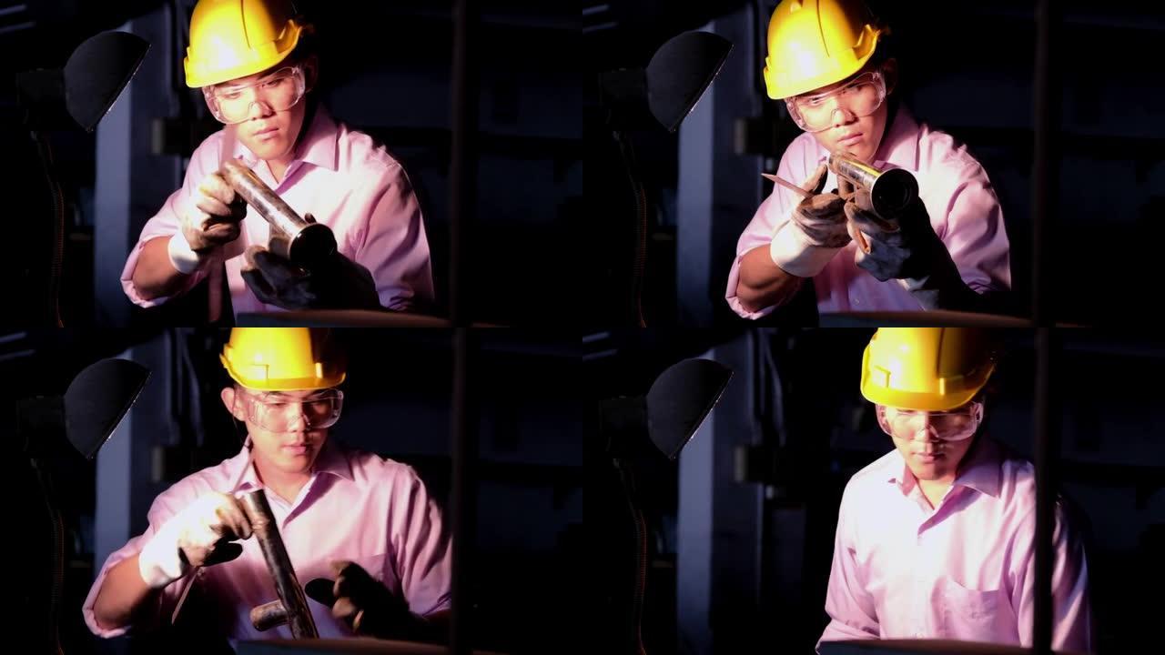 年轻的工程职业理念。年轻英俊的工程师在车间里测量他的切割金属零件以进行质量控制。穿着粉红色衬衫的中国
