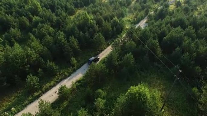 空中无人机在森林的道路上拍摄了一辆行驶中的suv汽车。