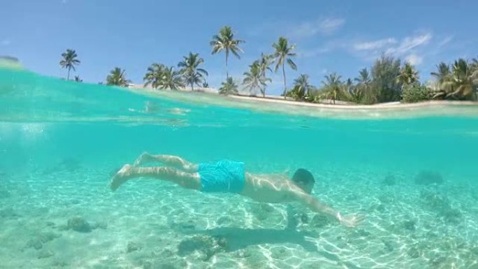 慢动作: 年轻人在热带岛屿的白色沙滩上游泳。