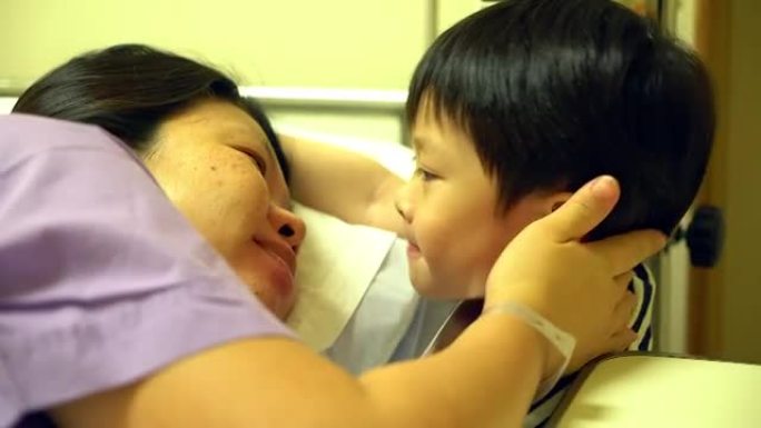 病人躺在床上检查脉搏或触摸她的儿子，小心概念。儿子亲吻她的母亲，因为病人躺在坏人身上。