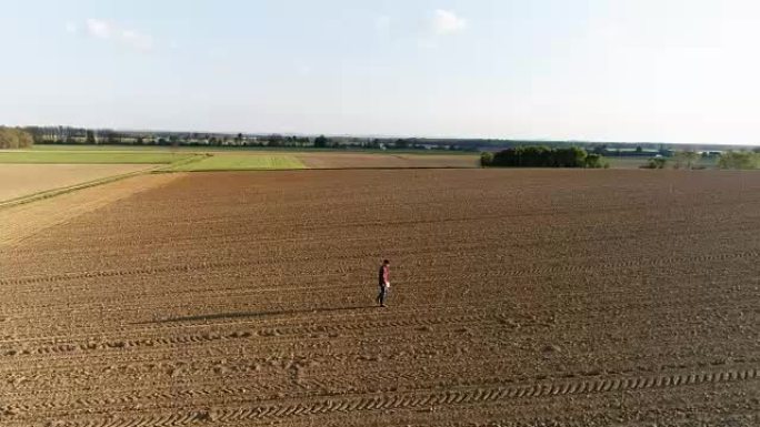 WS鸟瞰图农民在阳光明媚，广阔的乡村耕地中行走