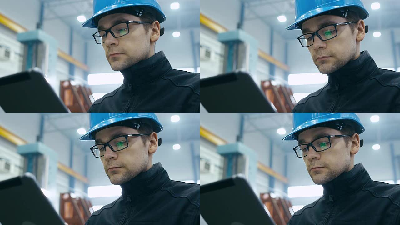 戴着安全帽的工厂工人正在使用平板电脑。