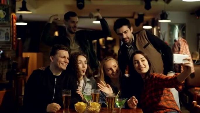 穿着便装的快乐年轻人在酒吧自拍。他们摆姿势，做鬼脸，笑着打手势。好回忆概念的有趣照片。
