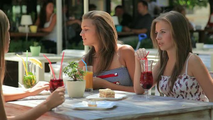 四名年轻女子在夏季户外人行道咖啡馆