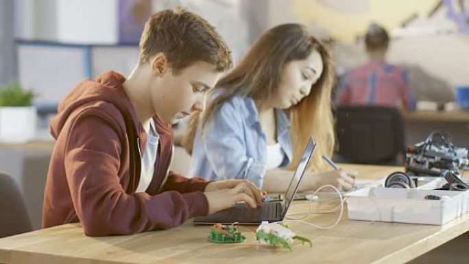 男孩课程项目的技术部分，女孩在学校为他们的科学/机器人/工程课程填写练习册。