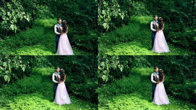 男人和女人，年轻幸福的已婚夫妇站在美丽的森林中