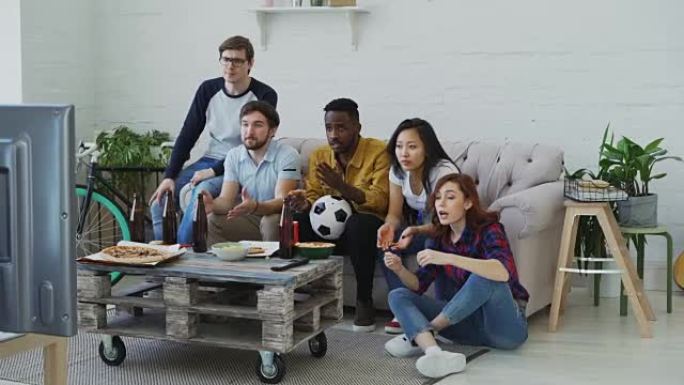 一群在电视上观看足球比赛的年轻朋友在家里一起吃零食和喝啤酒。女孩对自己的球队获胜感到满意，但男人感到
