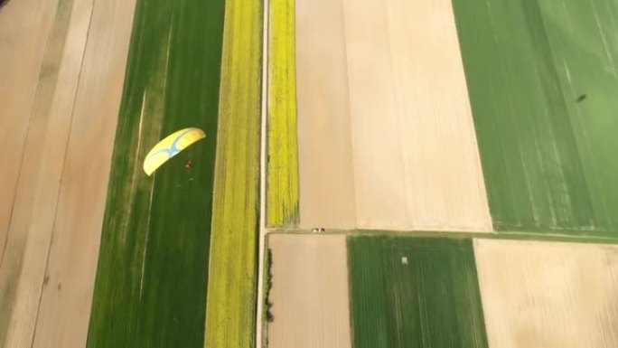 空中无人机视点滑翔伞在阳光明媚的乡村景观上跳伞，实时