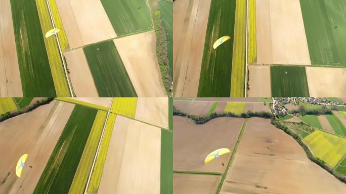 空中无人机视点滑翔伞在阳光明媚的乡村景观上跳伞，实时