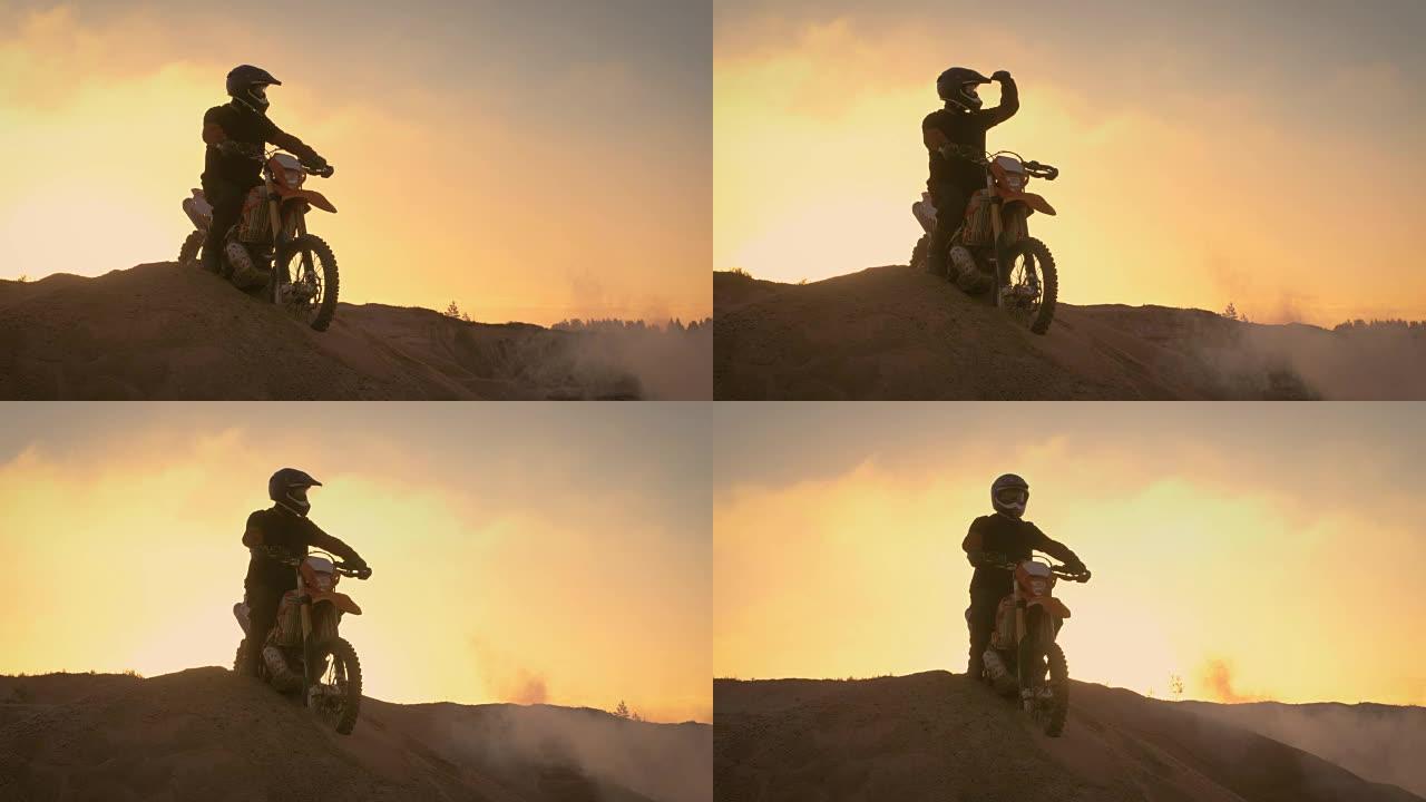 专业的越野摩托车手在他的耐久摩托车上壮观地站在越野沙丘上。在整个赛道上看得很远。