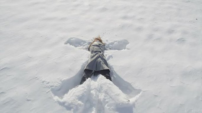 慢动作特写: 开朗的年轻女子制作雪天使