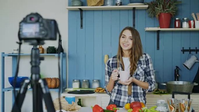 年轻迷人的女人在厨房的dslr相机上录制关于烹饪的视频食物博客