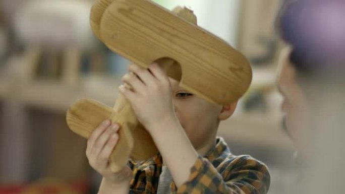 可爱的男孩玩木制飞机玩具