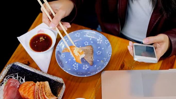 在4k餐厅使用手机时吃寿司的女人