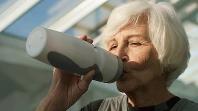 老年妇女在锻炼期间喝水