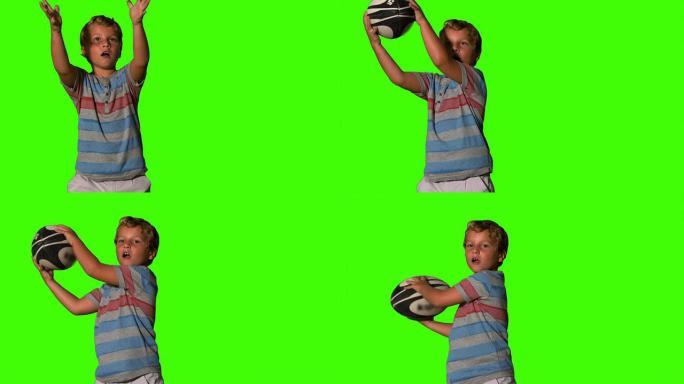 小男孩在绿色屏幕上捕捉橄榄球球