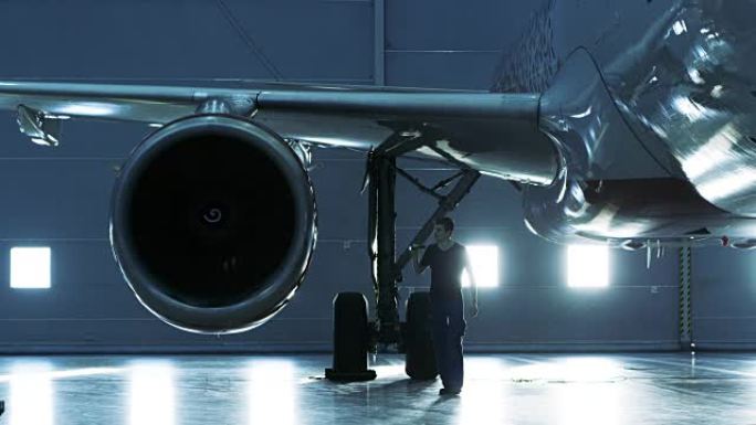 在机库中，飞机维修工程师/技术员/机械师目视检查飞机的喷气发动机。
