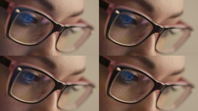 眼镜中的女人眼睛的特写镜头反映了正在工作的计算机屏幕。