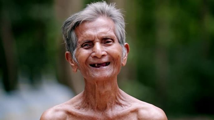 快乐的亚洲老人的肖像，有牙齿问题，笑着看着相机。