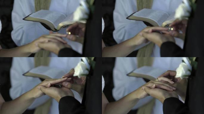 新郎在牧师面前将戒指戴在新娘的手指上
