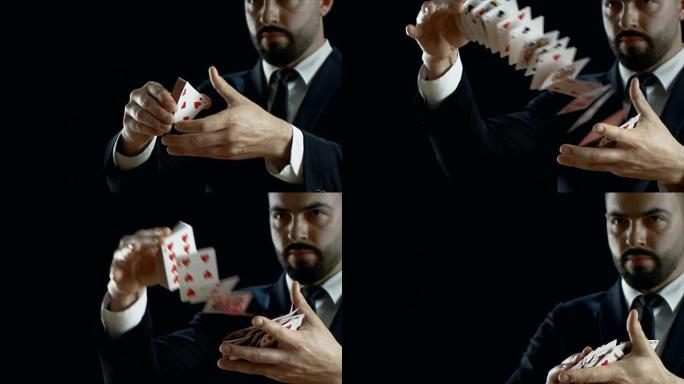 穿着黑色西装表演纸牌把戏的专业魔术师的特写镜头。在空中投掷和捕捉纸牌。花招。背景是黑色的。慢动作。