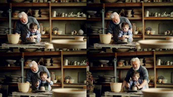 富有爱心的祖父经验丰富的波特正在教小男孩如何在波特的轮子上使用粘土。孙子在犯错误，耐心的爷爷在帮他。
