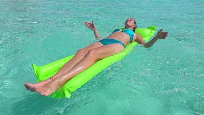 慢动作: 微笑的女人在海洋中的充气床上游泳