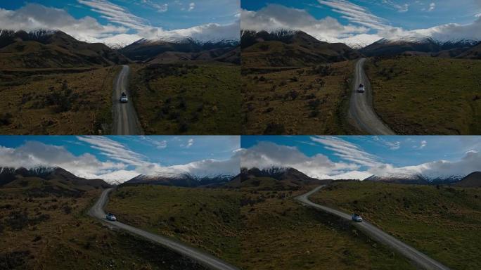 SUV在沙漠中驶向新西兰雪山山峰的鸟瞰图