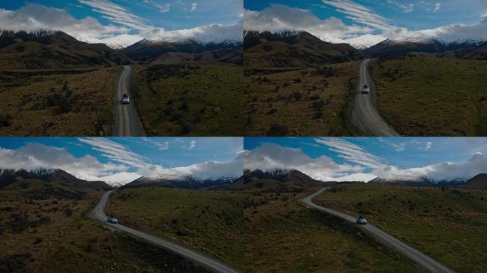 SUV在沙漠中驶向新西兰雪山山峰的鸟瞰图