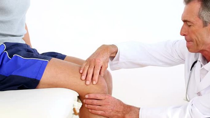 成熟的医生触摸运动员受伤的膝盖