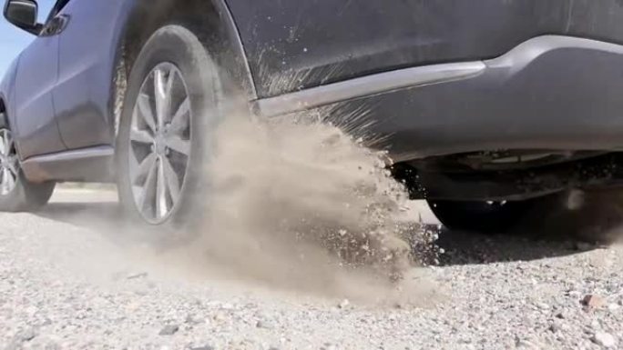 汽车启动并迅速开走，轮胎在砾石路面上扬起沙尘
