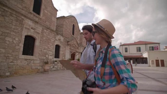 年轻夫妇带着地图在古老的石头建造的村庄里走来走去