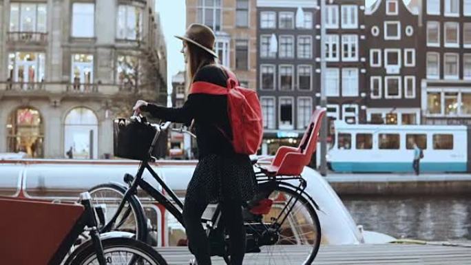 旅游小姐骑自行车去城市河码头。高加索女性站着，骑自行车神奇的老城。慢动作