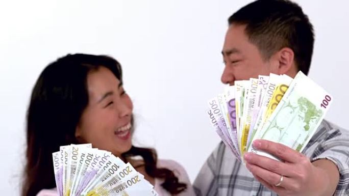 快乐的亚洲夫妇展示他的钱