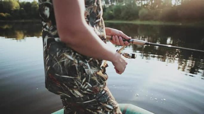用旋转的卷轴握住钓鱼竿的男性双手的特写视图。年轻人独自抓鱼