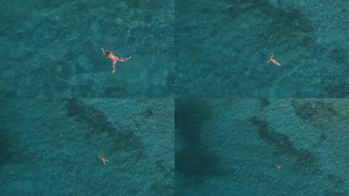 空中: 适合年轻女子在令人惊叹的水晶般清澈的海洋中的深水中游泳