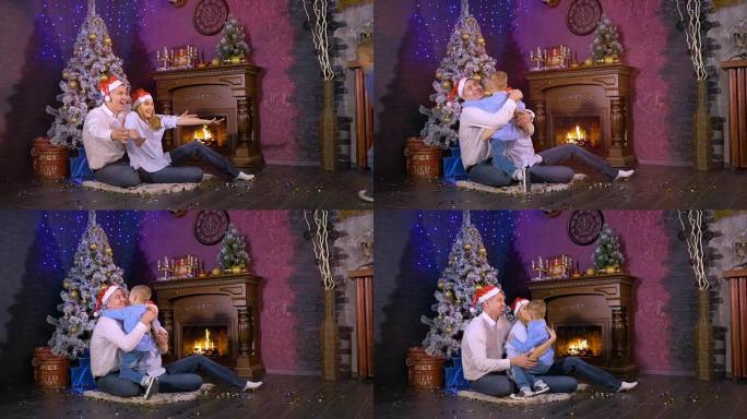 快乐的爸爸妈妈在圣诞壁炉旁拥抱他们的儿子。慢动作。