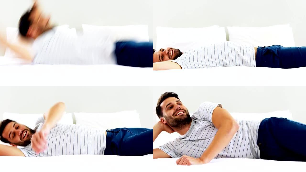 微笑的男人在卧室的床上跳来跳去