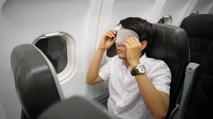 男子戴着眼罩睡眠面罩在飞机上睡觉