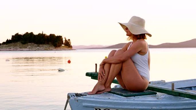 日落时，女人在一艘旧木船上放松