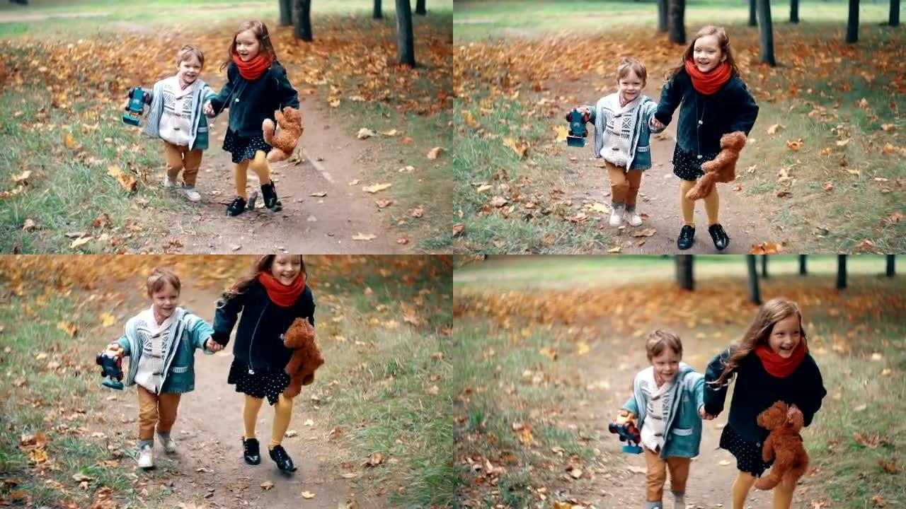 可爱的兄妹小男孩和女孩手牵手奔跑，带着玩具穿过公园慢动作的秋天小巷