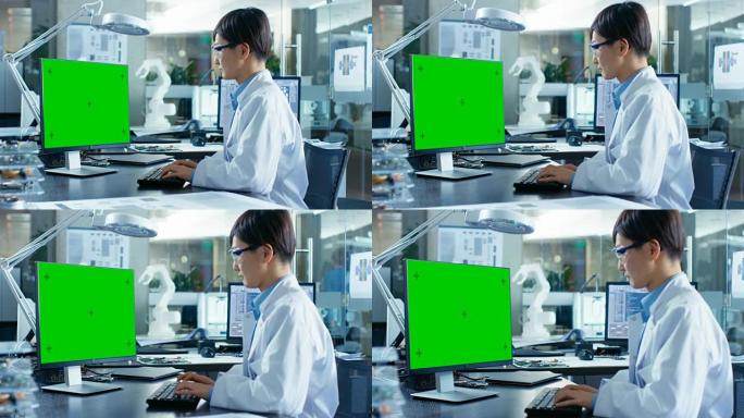 坐在办公桌前的亚洲科学家在带有绿屏模型的个人计算机上工作。在后台计算机科学研究实验室中使用机械臂模型