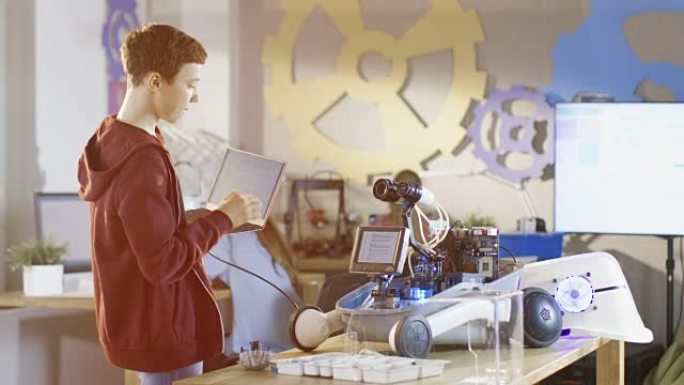 聪明的小男孩用笔记本电脑编程机器人。他正在为他的科学/机器人课建造机器人。