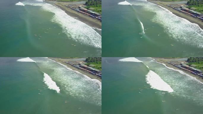 空中: 冲浪者在Canggu surfspot划着阵容并骑着泡沫波