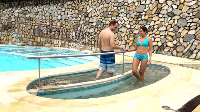 一对夫妇在水疗静修处在游泳池锻炼双腿