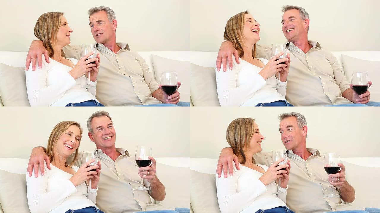成熟的夫妇一起在沙发上喝红酒