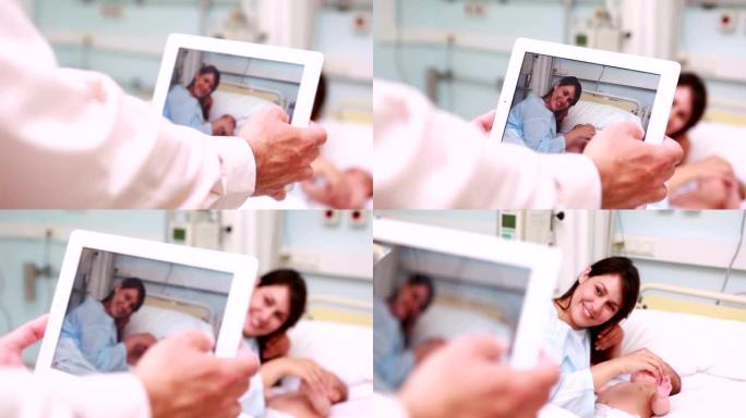 用平板电脑拍摄的微笑母亲和新生婴儿的照片