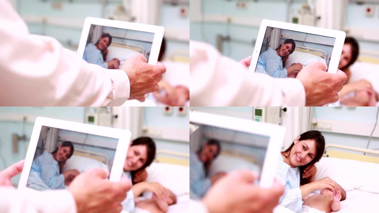 用平板电脑拍摄的微笑母亲和新生婴儿的照片